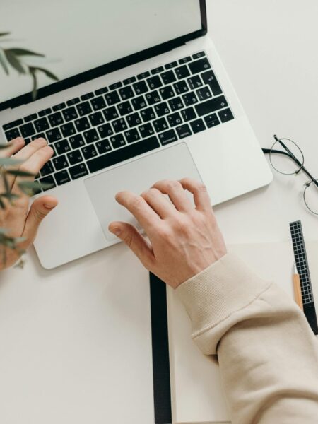 Free An overhead view of a person working on a laptop in a minimalist home office setting. Stock Photo